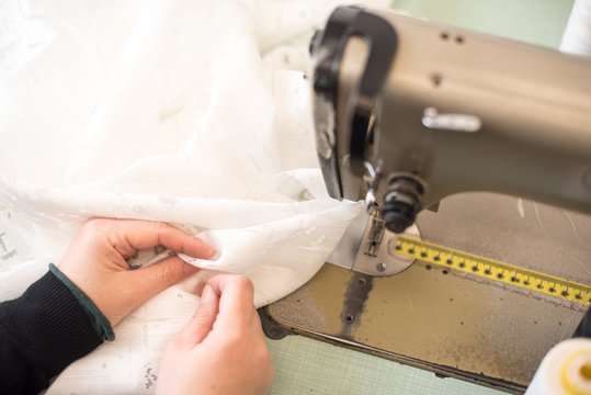 Mani di donna che cuce tessuto con macchina da cucire