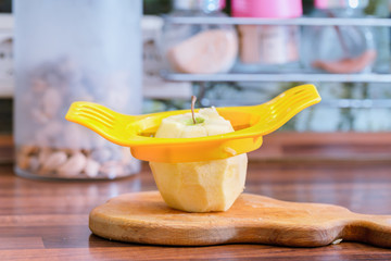 Device for cutting apple into slices and an apple on the kitchen table.