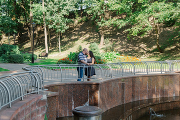 Two people in love are standing at the idle fountain in the park.