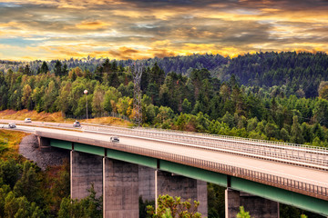 Fototapeta na wymiar Road with a concrete bridge through forest areas.