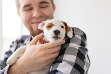 People, pet and dog concept - Close up portrait of man holding a cute jack russell terrier puppy