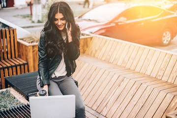 Happy latin woman with smartphone or laptop in city centre