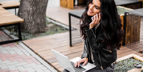 Happy latin woman with smartphone or laptop in city centre