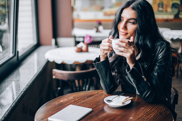 Young pretty spanish woman in cafe in city centre with tablet laptop