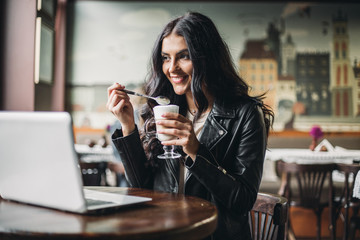 Young pretty spanish woman in cafe in city centre with tablet laptop