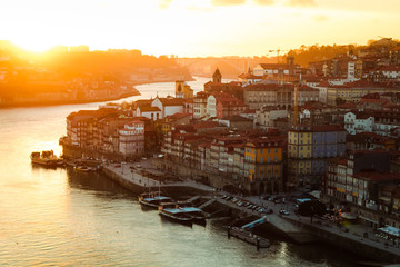 Dramatic sunset over the old city / old town of Porto with picturesque old buildings and boats as...