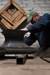 Blacksmith in workshop soldering metal object