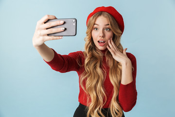 Naklejka premium Photo of beautiful girl 20s wearing red beret taking selfie on mobile phone