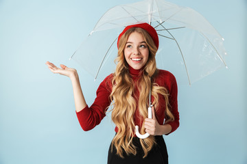 Portrait of friendly blond woman 20s with long hair standing under umbrella