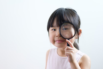 Little Asian girl child looking through a magnifying glass isolated on white background