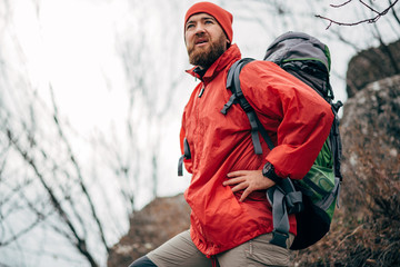 Portrait of young male hiking in mountains wearing red clothes exploring new place. Traveler...