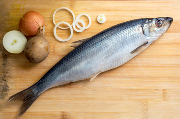 Salted herring with onion and potato on the old wooden background