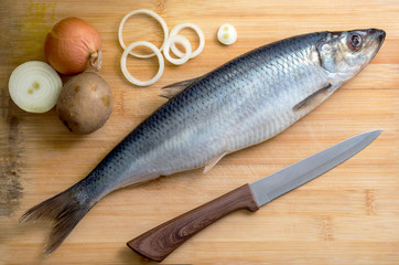 Salted herring with onion and potato on the old wooden background