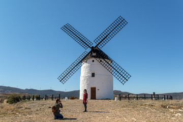 Pareja de turistas haciéndose fotos en un molino de viento tradicional en España.