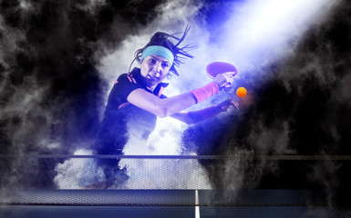 Woman playing ping pong on dark smoke background