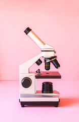 Microscope on soft pink pastel background.