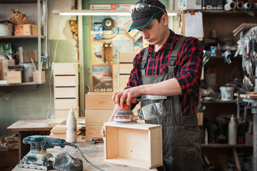 Worker grinds the wood box of angular grinding machine