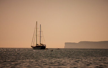 Yacht in the sea, mountain view, people are sailing in boats nearby.