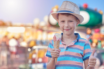 Cute boy is eating ice-cream he is enjoying his summer holidays and making like gesture.