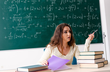 Young female math teacher in front of chalkboard  