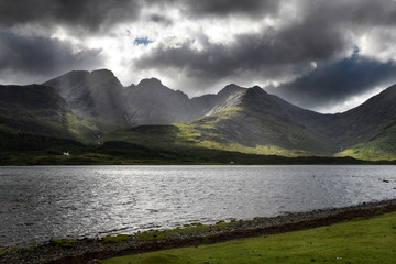 Sun rays on Bla Bheinn mountains outlier of the Black Cuillin with dark clouds and Loch Slapin from Torrin Isle of Skye Scotland UK