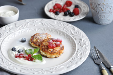 Cottage cheese pancakes with raspberry, blueberry, red currant berries. Gourmet breakfast. Cheesecakes are sprinkled with powdered sugar and decorated with mint. Close-up.