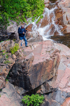 Man standing on rock near waterfall