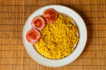 yellow rice on a plate with fried sausage