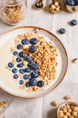 Healthy breakfast, a bowl with organic granola, chocolate pieces, fresh blueberries, hazelnuts and soya milk.