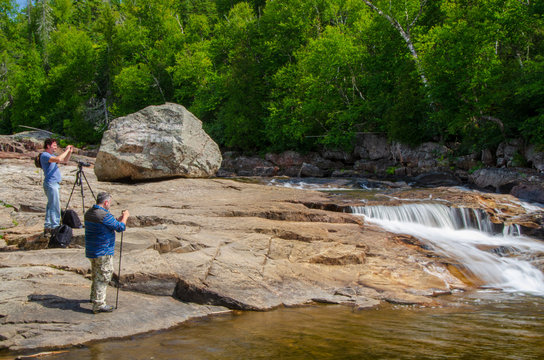 Photographers standing on rocks, photographing water fall