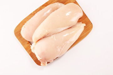Raw chicken breasts and spices on wooden cutting board, close up