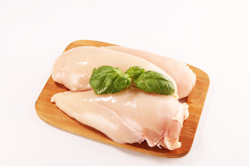 Raw chicken breasts and spices on wooden cutting board, close up