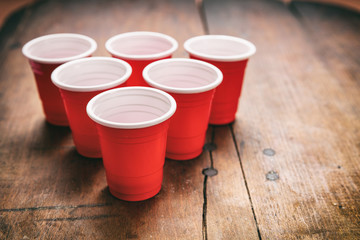 Beer pong. Plastic red color cups on wooden background