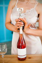 Girl opens a bottle of wine with a corkscrew