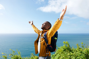 happy young african american male traveler with arms open outdoors