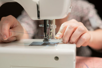 female tailor thread sewing machine on dark background close up