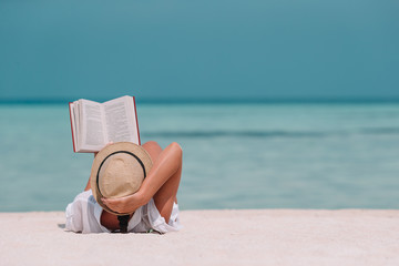 Young woman reading book during tropical maldivian beach