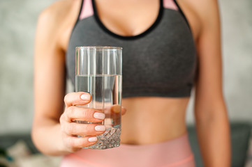 Woman in a tracksuit drinking a glass of water