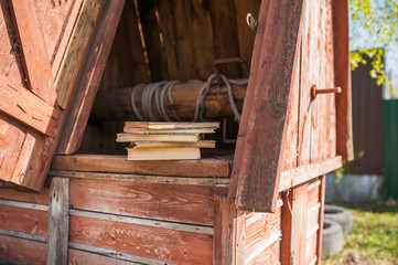 A stack of vintage books lie on a wooden old well