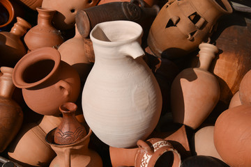 Fototapeta na wymiar The unique texture of old clay products - ceramic pots, jugs and lamps with a clay vessel with a broken handle in the center