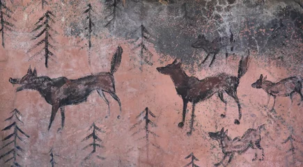 Tuinposter Prehistoric cave paintings - wolves and wood on beige stone © Evgeniya Fedorova