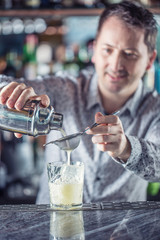 Professional barman making cocktail drink and pouring alcohol