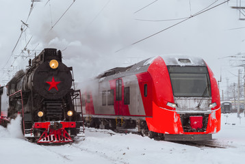 steam locomotive and modern multiple-unit train stand nearby at station