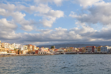 Fototapeta na wymiar A panorama of the harbor city of Chania. View of the emarald sea, interesting landscapes, colorful houses, a coast view from the cafe. The Mediterranean Sea. A popular tourist resort in the Greece.