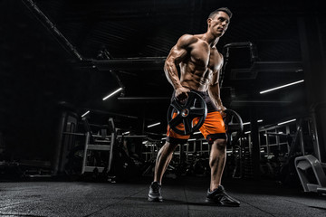 Obraz na płótnie Canvas Attractive tall muscular bodybuilder doing heavy deadlifts in moder fitness center.