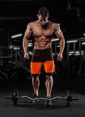 Fototapeta na wymiar Attractive tall muscular bodybuilder doing heavy deadlifts in moder fitness center