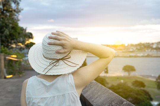 Woman with straw hat looking at the scenery and sunset.