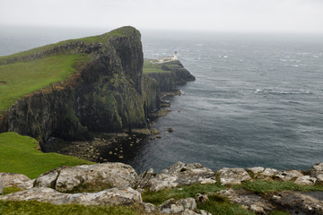 Neist Point Lighthouse in high winds and stinging rain with sheer basalt cliffs to Oisgill Bay Atlantic Ocean Isle of Skye Scotland UK