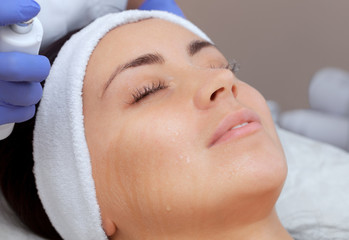 The procedure of steaming the skin of the face of a young woman before cleaning the skin in a cosmetology salon.