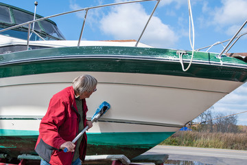 Caucasian man cleaning boat hull with brush